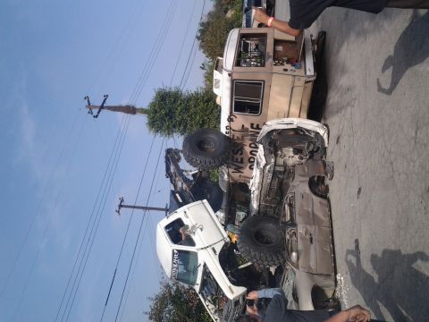 1986 Ford Bronco - Two custom off-road vehicles, a white truck and a tan RV, are seen in a precarious situation.