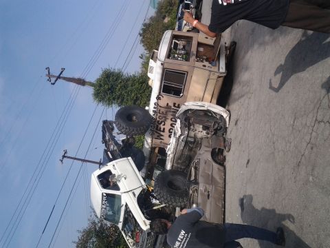1986 Ford Bronco - Two off-road trucks are wrecked, one is overturned. Visible text on one truck reads 'WESSEL GOODONE'.