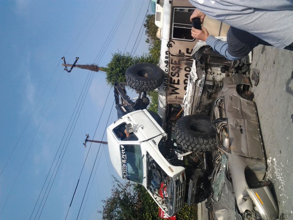 Two wrecked off-road trucks, one on its side, with large tires and damage