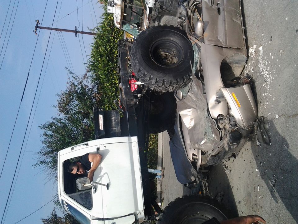 Two heavily damaged vehicles, one a white truck cab, the other a silver car, on a street