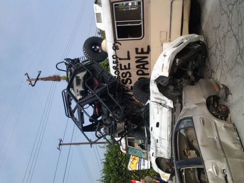 1986 Ford Bronco - Multiple vehicles are involved in a collision, with one utility vehicle precariously balanced.