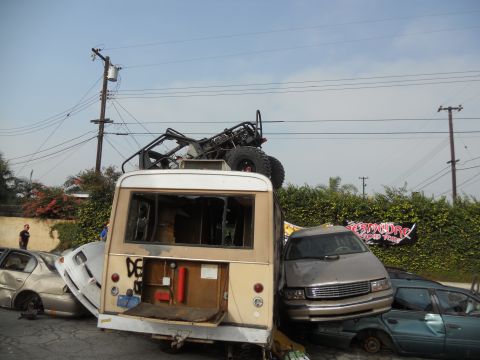 1986 Ford Bronco - A chaotic scene of damaged vehicles, including a bus and a sedan, with a buggy perched atop the bus.