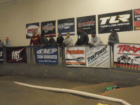 1986 Ford Bronco - Spectators watch a remote control car race on an indoor track, with various sponsor banners displayed overhead.