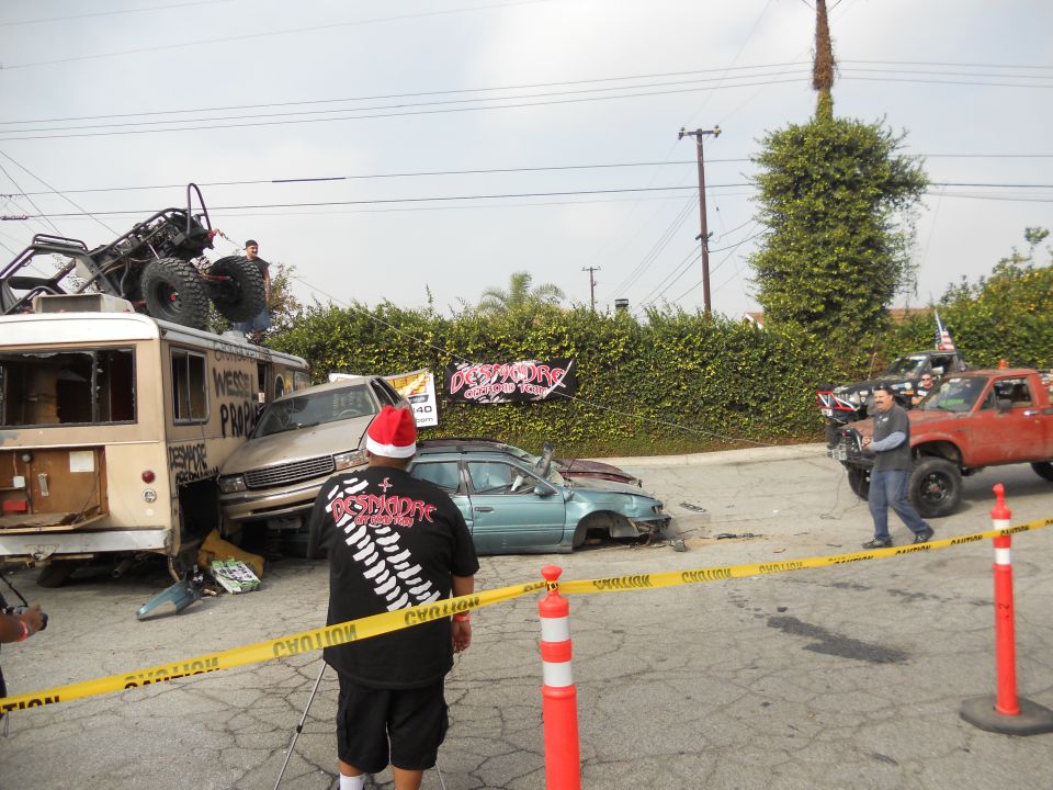 Scene of multiple wrecked vehicles, including a bus and cars, with a custom buggy on top of the bus
