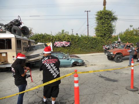 1986 Ford Bronco - A chaotic scene several damaged vehicles and off-road trucks, with individuals wearing Santa hats.
