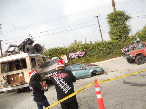 1986 Ford Bronco - A chaotic scene with multiple vehicles, including off-roaders and a wrecked car, under a cloudy sky.