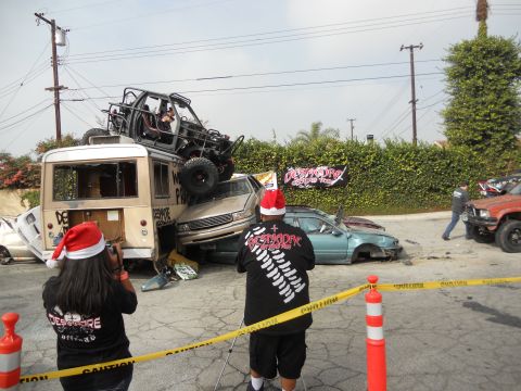 1986 Ford Bronco - A chaotic scene with multiple vehicles piled up, including a buggy on top of a bus, under a cloudy sky.
