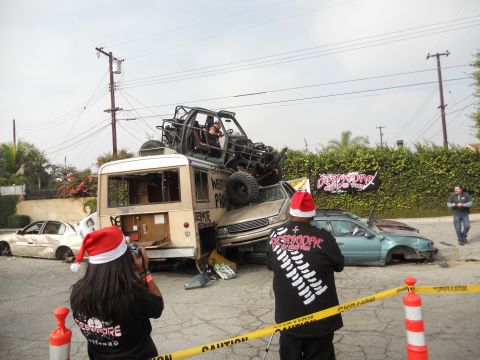 1986 Ford Bronco - A bizarre Christmas scene unfolds with multiple vehicles piled up and onlookers in festive hats.