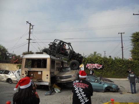1986 Ford Bronco - A chaotic scene with multiple wrecked vehicles, including a bus and a buggy, under a cloudy sky.