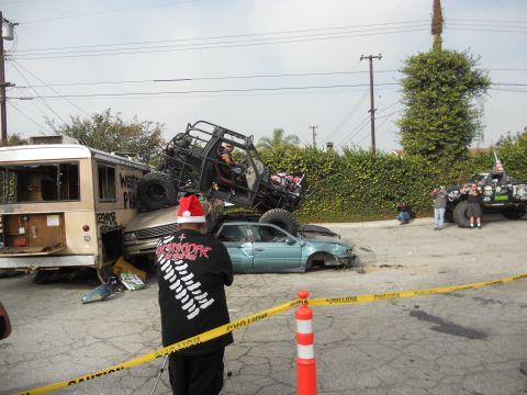 1986 Ford Bronco - Multiple wrecked vehicles are piled up, with an off-road buggy on top of a car and bus.