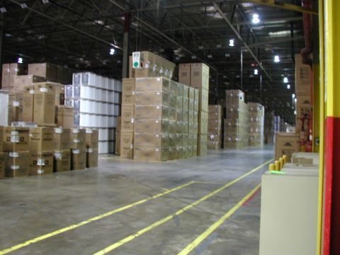 1998 Ford Taurus - A wide view of a warehouse interior filled with rows of stacked boxes and containers.