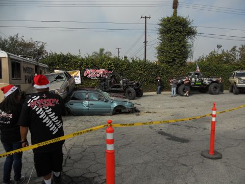 1986 Ford Bronco - A scene of multiple damaged vehicles, including cars and off-road trucks, with caution tape cordoning off the area.