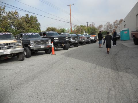 1986 Ford Bronco - A group of modified off-road vehicles are parked in a line, displaying custom decals on their windshields.