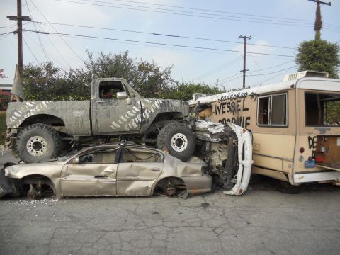 1986 Ford Bronco - Multiple wrecked vehicles are stacked and damaged in a scene that appears to be a junkyard or demolition derby aftermath.
