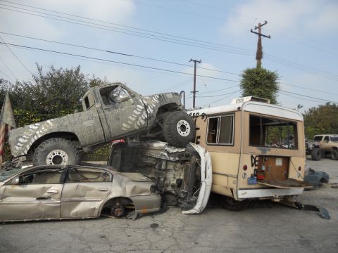 1986 Ford Bronco - A chaotic scene with a truck precariously balanced atop other wrecked vehicles.