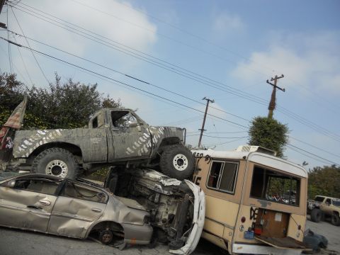1986 Ford Bronco - A chaotic scene of multiple damaged vehicles piled up, with a pickup truck precariously balanced.