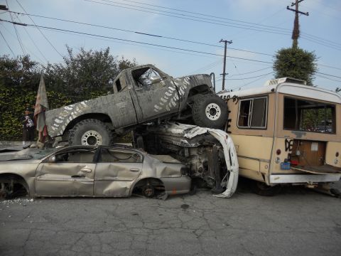 1986 Ford Bronco - A chaotic scene with multiple vehicles in disarray, including a crushed car and a truck precariously balanced.