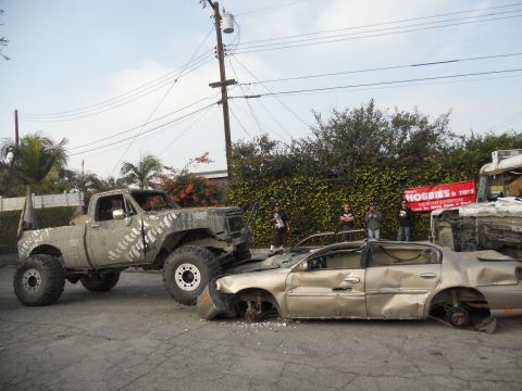 1986 Ford Bronco - A lifted pickup truck has crushed a sedan, with a "Hobbies & Toys" banner in the background.