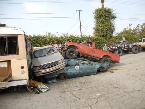 1986 Ford Bronco - A chaotic scene of damaged vehicles piled atop one another in an outdoor lot.