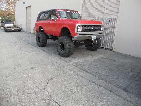 1986 Ford Bronco - This lifted SUV has a custom banner and is parked next to a trailer with another vehicle.