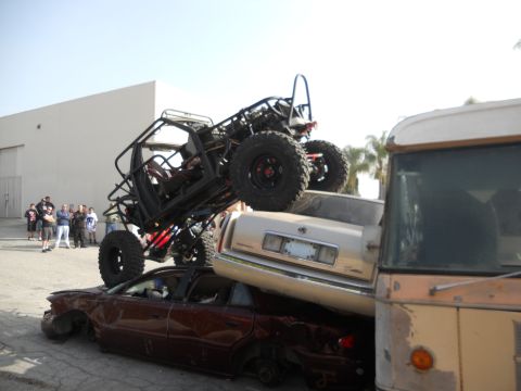 1986 Ford Bronco - A custom off-road buggy is precariously balanced atop a pile of wrecked vehicles.