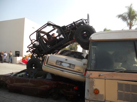1986 Ford Bronco - A heavily modified off-road vehicle is piled on top of other cars in a junkyard scene.