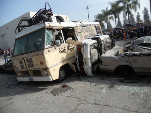 1986 Ford Bronco - Scene of multiple wrecked vehicles, including a bus and overturned car, with visible text on the bus.