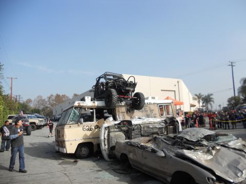 1986 Ford Bronco - A chaotic scene with multiple vehicles in disarray, including a dune buggy perched on a van.