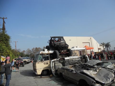 1986 Ford Bronco - A chaotic scene with an off-road buggy perched precariously on a stack of wrecked vehicles.