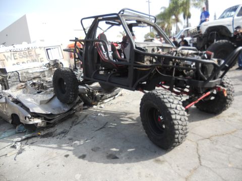 1986 Ford Bronco - Custom off-road buggy with roll cage and large tires sits beside wrecked vehicles.