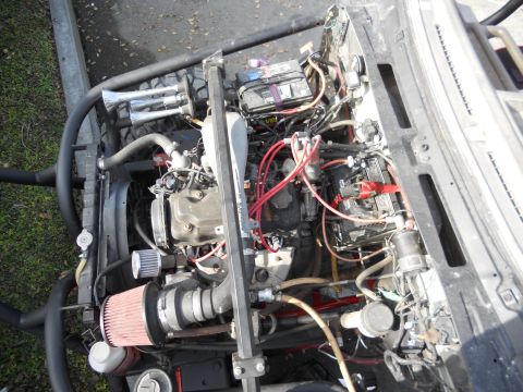 1986 Ford Bronco - The engine bay features dual batteries, an aftermarket air intake, and chrome air horns, suggesting custom modifications.