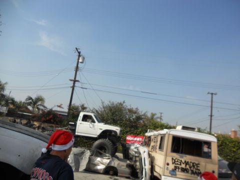 1986 Ford Bronco - A modified white pickup truck is seen in a junkyard with other vehicles and a person wearing a Santa hat.