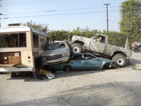 1986 Ford Bronco - Multiple wrecked vehicles are piled up in a heap, with a lifted pickup truck on top.