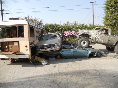 1986 Ford Bronco - Multiple vehicles and a bus are wrecked and piled up in a scene of destruction.