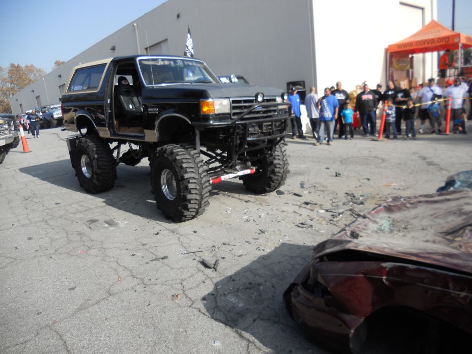 lifted black Bronco with tan top, front end damaged car in foreground
