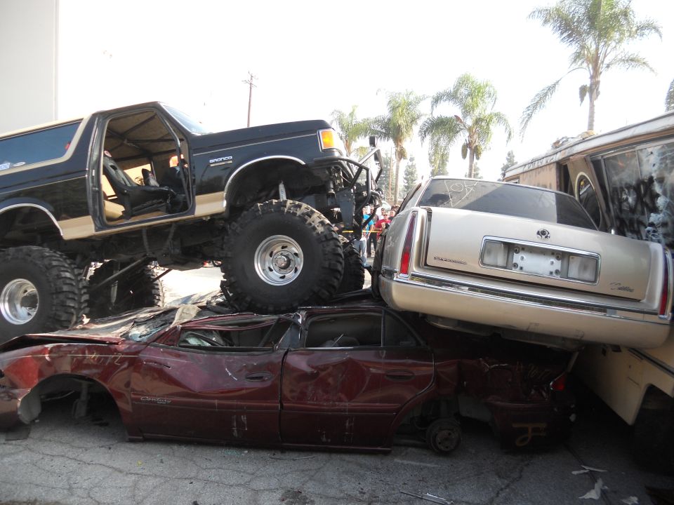 Lifted black 1986 Ford Bronco on top of crushed cars