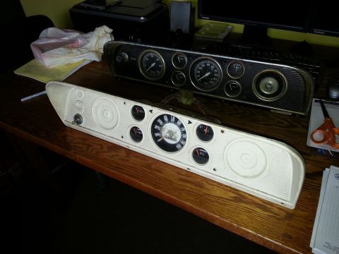 1967 Ford F-100 - A white and black dashboard instrument cluster, likely from a 1967 Ford F-100, is displayed on a wooden surface.
