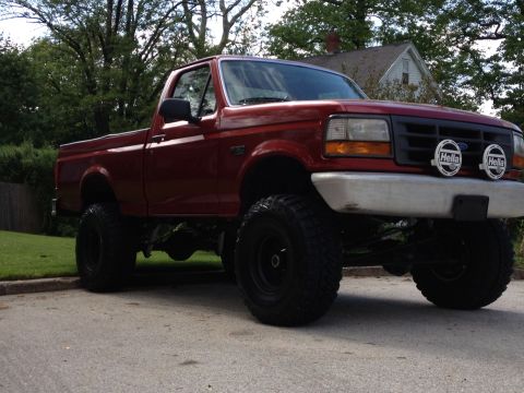 1996 Ford F-150 - This lifted 1996 Ford F-150 pickup truck features prominent Hella driving lights mounted on the front bumper.