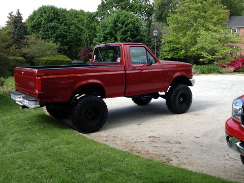 1996 Ford F-150 - Red 1996 Ford F-150 pickup truck with a lift kit and large off-road tires.