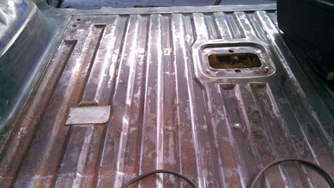 1979 Ford Bronco - The ribbed metal floor of a truck bed shows signs of wear and has a rectangular opening.