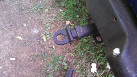 1979 Ford Bronco - A trailer hitch receiver is shown attached to the rear of a vehicle, with grass and dirt visible around it.