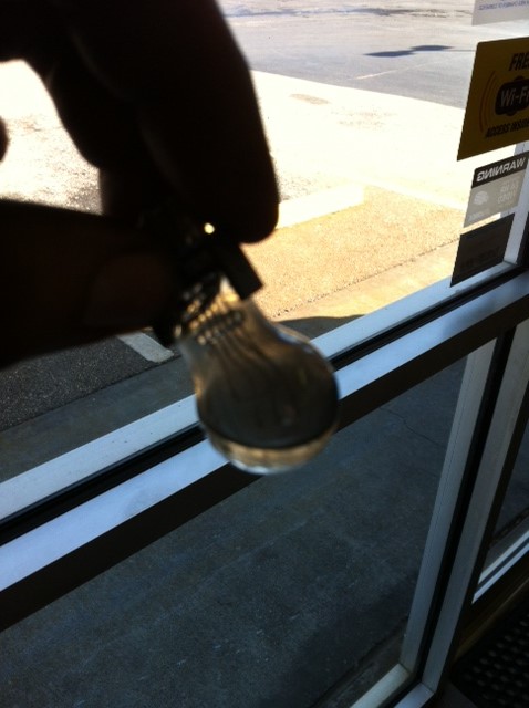 1996 Ford F-150 - A hand holds a small light bulb in front of a window with a 'Free Wi-Fi' sign.