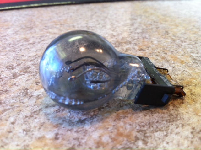 Used light bulb with blackened glass and metal contacts on a speckled countertop