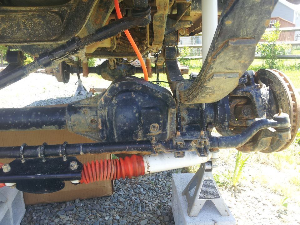 close-up of a vehicle's rear axle, leaf springs, and suspension components on jack stands