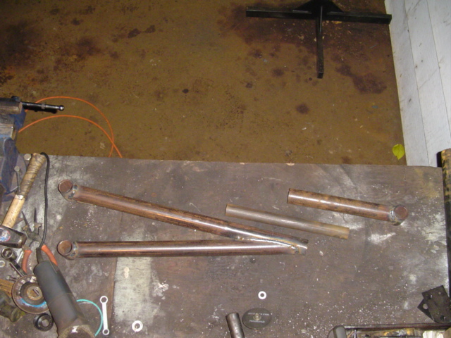 Several metal tubes, some with flared ends, lie on a workbench next to tools