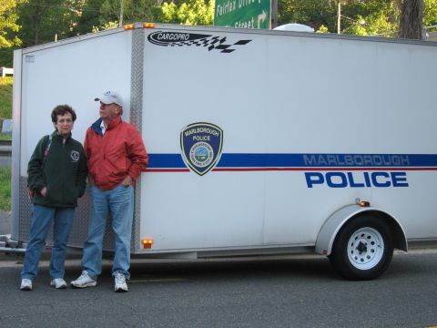 1991 Ford LTD Crown Victoria - man and woman in casual jackets stand beside a white CargoPro enclosed trailer marked Marlborough Police with a department seal.