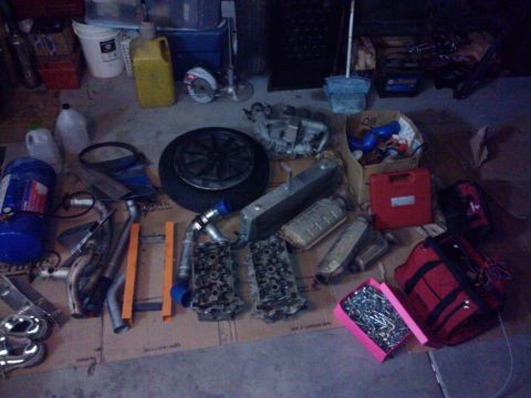 1995 Ford Probe - Various automotive components and a toolbox are laid out on the floor of a garage.