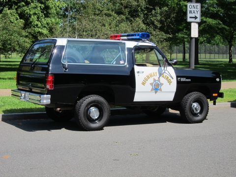 1991 Ford LTD Crown Victoria - Rear view of a black-and-white Dodge Ramcharger marked Highway Patrol parked beside a One Way road sign on a grassy roadside.