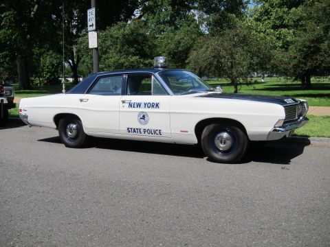 1991 Ford LTD Crown Victoria - white New York State Police sedan with black roof and single beacon parked at an angle on a tree-lined roadside.