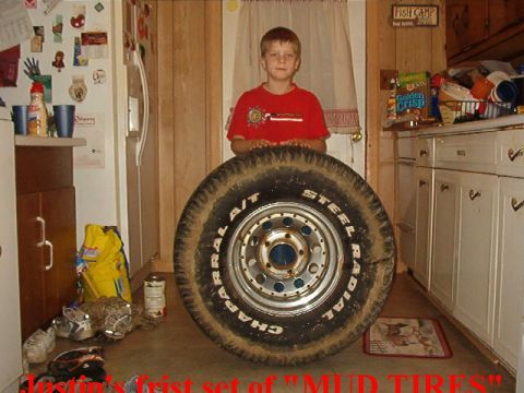 1989 Ford Bronco - A boy poses with a large off-road tire in what appears to be a kitchen or utility room.